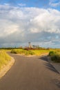 Vertical shot of a country road surrounded by green grass in Vlissingen, Zeeland, Netherlands