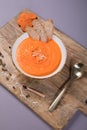 Vertical shot of Creamy Roasted Carrot Soup on plate on a cutting board on purple background Royalty Free Stock Photo