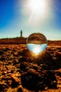 Vertical shot of a crystal ball with a lighthouse on the rocky seashore