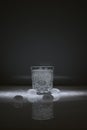 Vertical shot of crystal water glass, ice cubes and waterdrops around, against a dark background Royalty Free Stock Photo