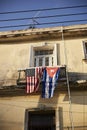 Vertical shot of a Cuban and an American flag hanging on a balcony Royalty Free Stock Photo