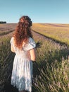 Vertical shot of curly girl with white dress on the Lavender field in Hitchin, United Kingdom