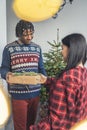 vertical shot of a cute couple exchanging gifts in front of a Christmas tree Royalty Free Stock Photo