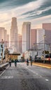 Vertical shot of cyclists riding on an empty street towards of kyscrapers of Los Angeles at sunset