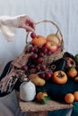 Vertical shot of dainty hand holding a grape over a table filled with twelve different round fruits