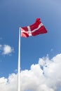 Vertical shot of the Danish flag with the beautiful clouds in the blue sky in the background Royalty Free Stock Photo