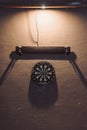 Vertical shot of darts target hanging from wall under light Royalty Free Stock Photo