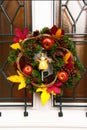 Vertical shot of a decorative autumn wreath with apples and pinecones hanging on a door