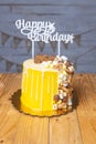 Vertical shot of a delicious birthday cake decorated with chocolate pieces on a wooden table