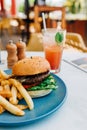 Vertical shot of a delicious burger and some french fries and a glass of cocktail on a table Royalty Free Stock Photo