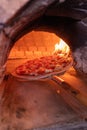 Vertical shot of a delicious cheesy pepperoni pizza inside the brick stone oven