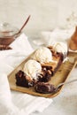 Vertical shot of delicious peanut butter swirl brownies with ice cream on top on a white table