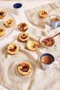 Vertical shot of delicious Portuguese egg tarts with a cup of espresso on a white table