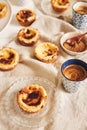 Vertical shot of delicious Portuguese egg tarts with a cup of espresso on a white table