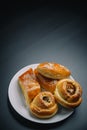 Vertical shot of delicious sesame buns or pies on white plate on black wooden table background. Tasty unhealthy snack for lunch. Royalty Free Stock Photo