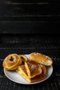 Vertical shot of delicious sesame buns or pies on white plate on black wooden table background Royalty Free Stock Photo