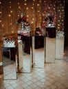 Vertical shot of a dessert corner of a restaurant with sweets and flower decors put on mirror tables