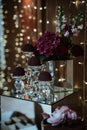 Vertical shot of a dessert corner of a restaurant with sweets and flower put on a mirror table