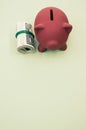 Vertical shot of dollar bills and a piggy bank on a green surface Royalty Free Stock Photo