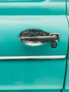 Vertical shot of a door handle on a teal colored vintage car Royalty Free Stock Photo