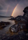 Vertical shot of double rainbow in the sky over a rocky coast in skjervoy, Norway Royalty Free Stock Photo