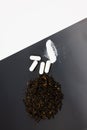 Vertical shot of dried black tea leaves with caffeine pills isolated on a grey and white background