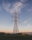 Vertical shot of an electric tower on a grassy field under a blue sky Royalty Free Stock Photo