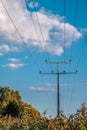Vertical shot of electrical wires from a high voltage tower against blue cloudy sky Royalty Free Stock Photo