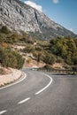 Vertical shot of an empty highway surrounded by dramatic mountains on a sunny day in Croatia Royalty Free Stock Photo