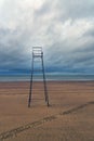 Vertical shot of an empty lifeguard chair on a beach shore with a cloudy sky in the background Royalty Free Stock Photo