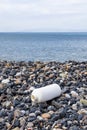 Vertical shot of an empty plastic bottle on a pebble beach, the concept of plastic pollution. Royalty Free Stock Photo