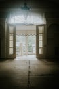 Vertical shot of an empty room with a chandelier on the ceiling and open balcony doors Royalty Free Stock Photo