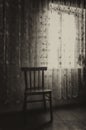 Vertical shot of an empty room with windows, curtains and a wooden chair