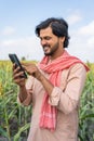 vertical shot of farmer busy using mobile phone at agricultural farm land - concept of technology, connection and modern