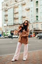 Vertical shot of a fashionable woman in sunglasses and stylish outfit hugging her small dog - york terrier, busy city street on a Royalty Free Stock Photo