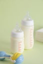 Vertical shot of feeding bottles with baby food, baby rattle and disposable towels Royalty Free Stock Photo