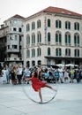 Vertical shot of a female doing an acrobatic show with a hoop at the Split Promenade, Croatia
