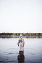 Vertical shot of a female wearing a biblical robe while walking in water with blurred background Royalty Free Stock Photo