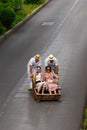 Vertical shot of females getting a ride on a toboggan down the hill in Madeira Portugal