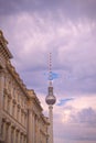 Vertical shot of the Fernsehturm Berlin and building fragment against a cloudy dusk sky