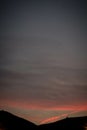 Vertical shot of fiery red sunset seen through a mountain silhouette - perfect for wallpapers