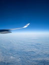 Vertical shot of a Finnair airplane wing flying in the blue sky with white clouds below