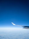 Vertical shot of a Finnair airplane wing flying in the blue sky with white clouds below