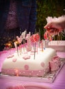 Vertical shot of a first birthday fondant cake with pink decorations, lollipops, and candles Royalty Free Stock Photo