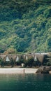 Vertical shot of the fisherman on the shore with huts and lush trees in the background