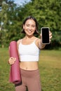 Vertical shot of fit and healthy young asian woman, shows smartphone screen with her workout stats, recommends telephone