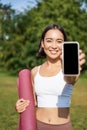 Vertical shot of fit and healthy young asian woman, shows smartphone screen with her workout stats, recommends telephone