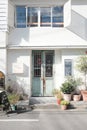 Vertical shot of flower pots in front of a white house with blue doors Royalty Free Stock Photo