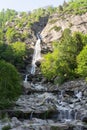 Vertical shot of flowing waterfall falling from rocks surrounded by trees Royalty Free Stock Photo