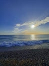 Vertical shot of a foamy tide at a pebbled coast under the blue sky